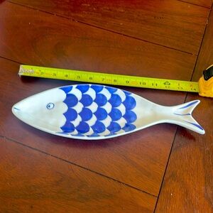 Small white with blue scales fish shaped hors d’oeuvres dish.